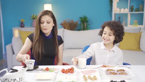 madre y hijo felices desayunando en casa, el niño bebiendo leche.