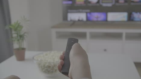 someone's hand with a remote control navigates through the tv menu for a programme or film to watch