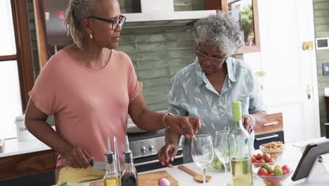 Amigas-Afroamericanas-Mayores-Cocinando,-Preparando-Verduras-Y-Usando-Tabletas,-Cámara-Lenta