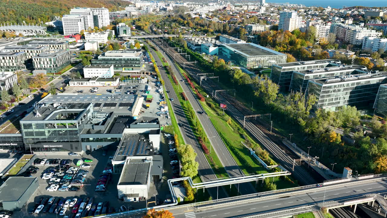 Drone footage of Gdynia with modern office buildings, train tracks, and roads leading to the Baltic Sea