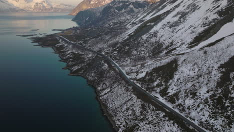 High-altitude-wide-angle-aerial-view-mountain-road-with-snow-and-lake