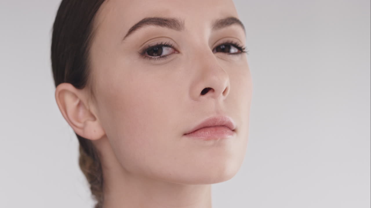 retrato de belleza de una mujer con un rostro hermoso inclinando la cabeza hacia arriba en cámara lenta concepto de cuidado de la piel sobre un fondo gris en cámara lenta dragón épico rojo