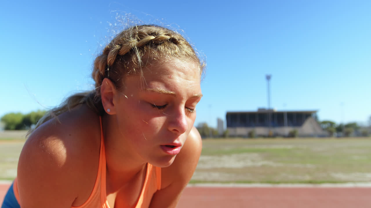 vista frontal de una atleta caucásica tomando un descanso en una pista deportiva 4k