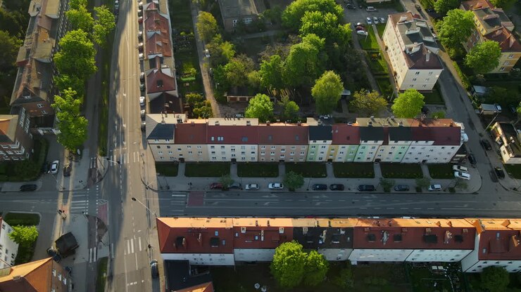 Volo aereo laterale su un incrocio stradale in un'area residenziale di Danzica, Polonia, con parcheggi privati lungo la strada vicino all'edificio, vista dall'alto.