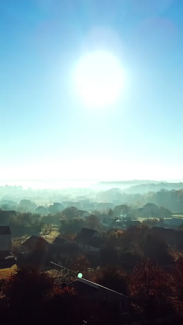 Aerial top view of the small houses at sunrise. Rural landscape of house roofs, roads and tree tops in spring or summer day. Camera moves forward. Vertical video