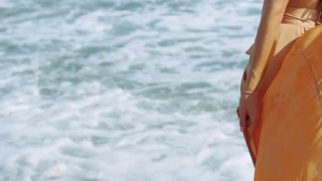 woman-walks-by-the-sea-holding-her-flying-pareo