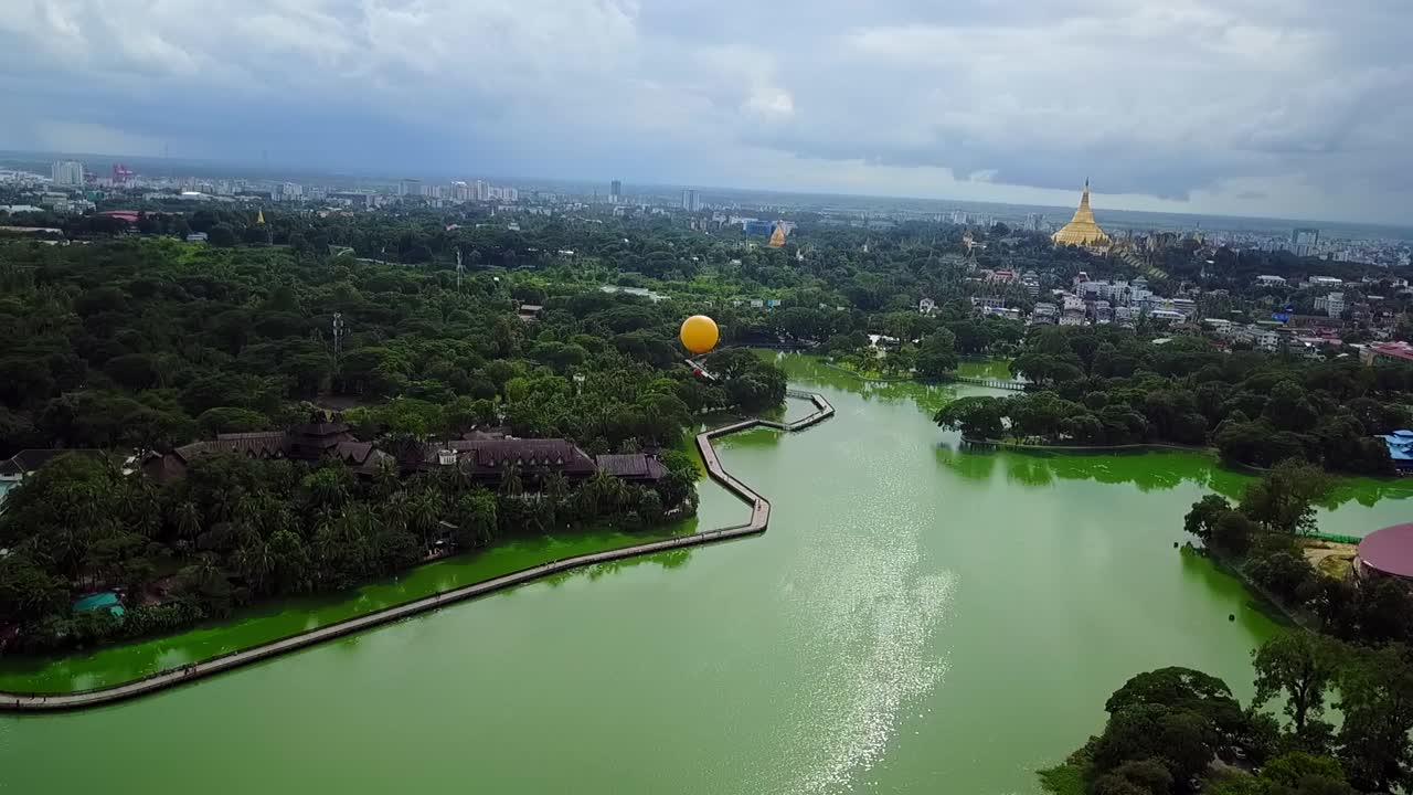A panoramic aerial view of Yangon, Myanmar, highlighting the serene Kandawgyi Lake and the magnificent Shwedagon Pagoda, offering a perspective of the city’s landscape and cultural landmarks