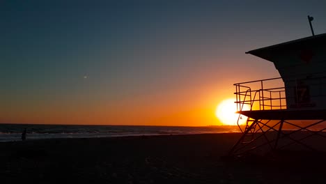 Slow-sunset-shot-moving-towards-and-passing-Lifeguard-house-:-tower-at-San-Buenaventura-State-Beach-in-Ventura,-California,-United-States