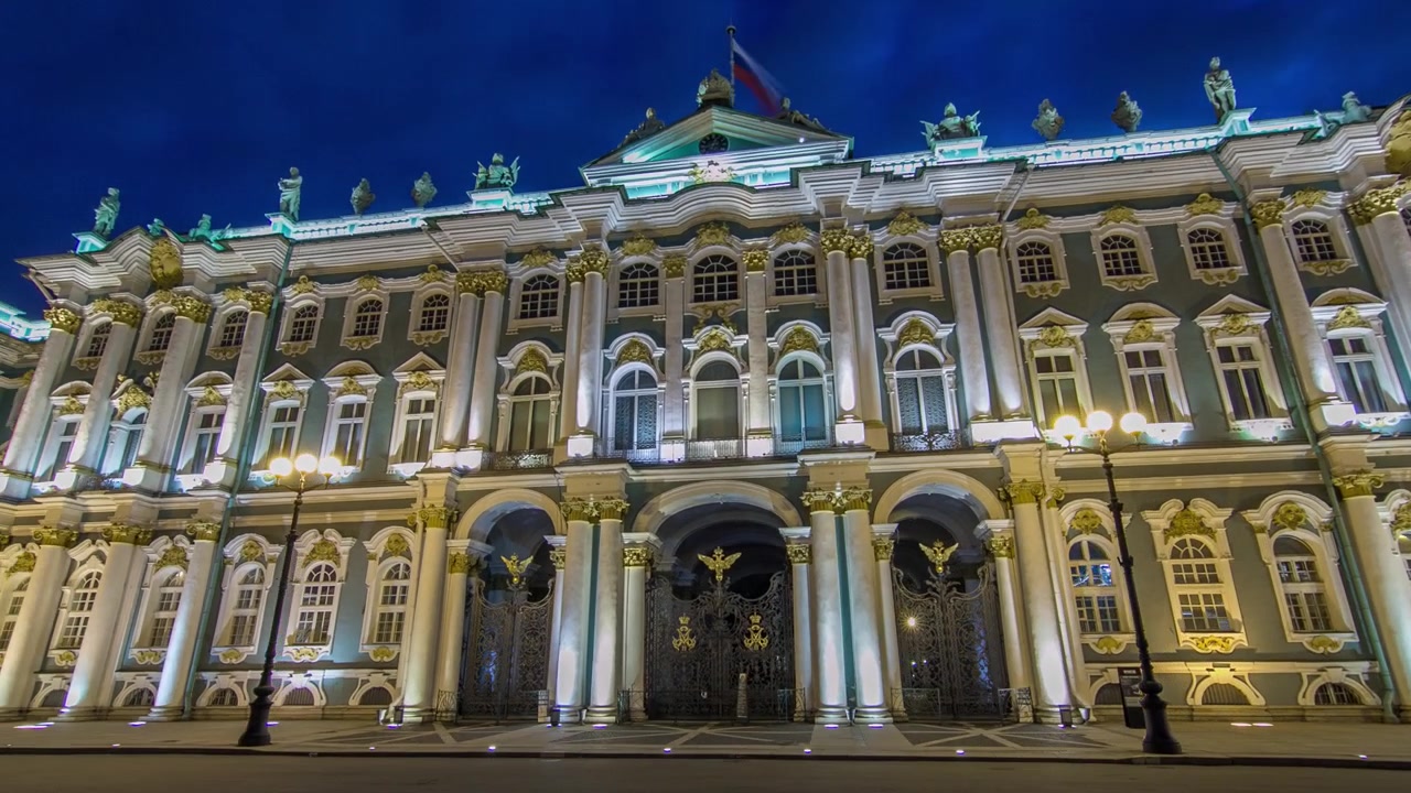 Timelapse Hyperlapse d'une vue de face illuminée du Palais d'Hiver à Saint-Pétersbourg, ancienne résidence officielle des monarques russes, sur fond de la splendeur de la Place du Palais.