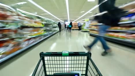 a shopping cart moving through a grocery store aisle.