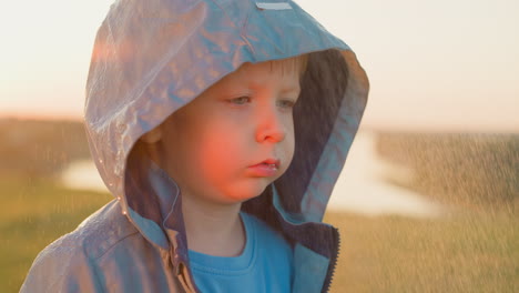 indignant toddler stands on riverbank forsaken child wrapped tightly in hooded cloak navigates