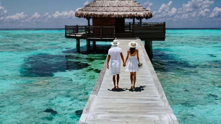 Aerial video captures a couple walking hand in hand on a wooden pier over turquoise waters