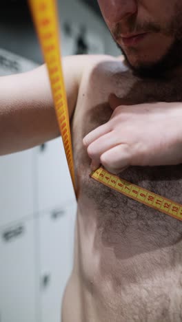 man measuring his chest in a locker room