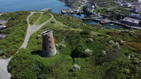 puerto amlwch ladrillo rojo en desuso abandonado molino de viento vista aérea norte de anglesey gales lento aumento tiro inclinando hacia abajo