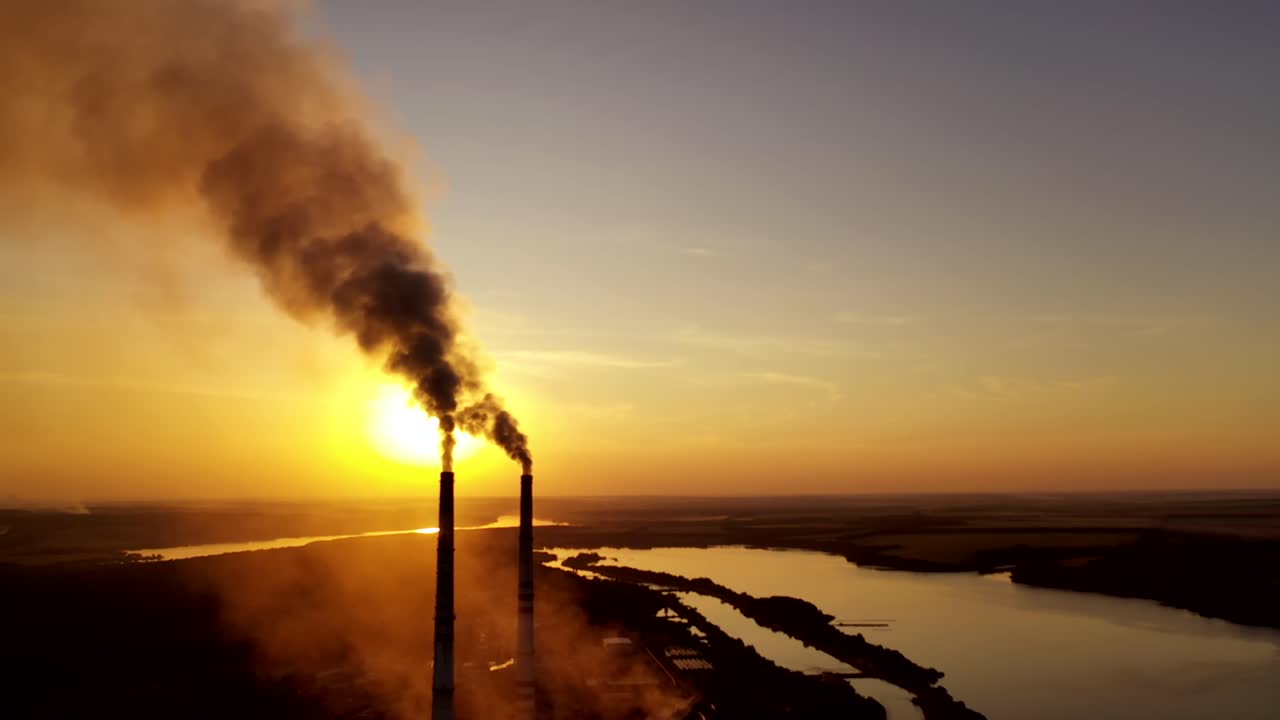 Smoking pipes against sunset. Industrial chimneys with heavy smoke causing air pollution