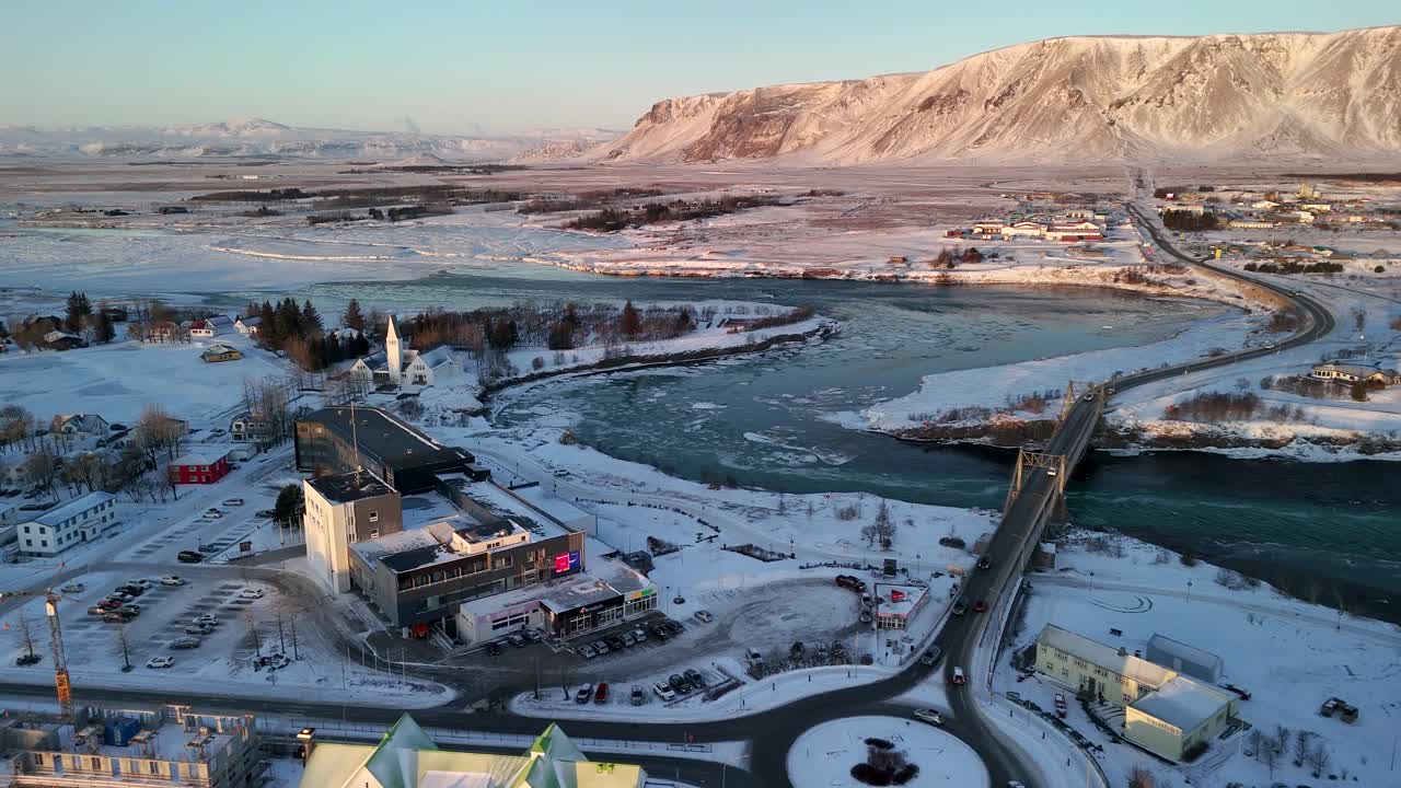 подвесной мост olfusarbru с selfosskirkja на заднем плане в селфоссе, исландия.
