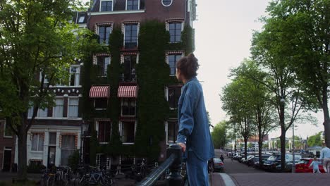 una mujer joven mirando las casas del canal de ámsterdam.