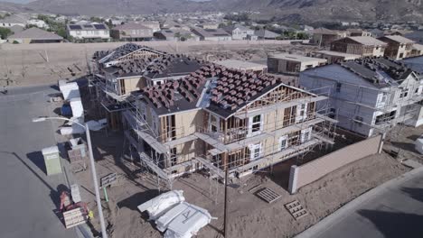 a drone swiftly ascends straight up, tilting and locking its view on a partially built house, providing a unique and focused perspective