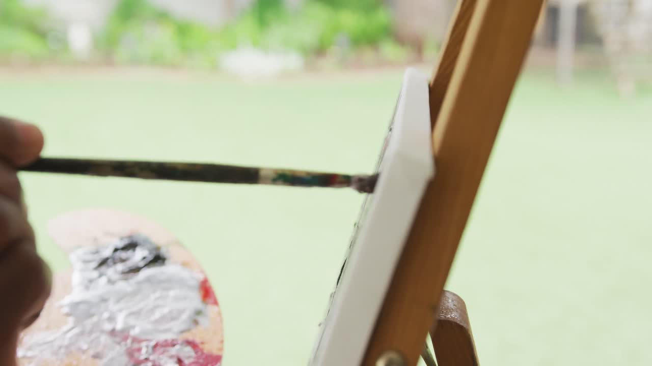 아프리카계 미국인 노인 남자가 밖에서 그림을 그리는 영상