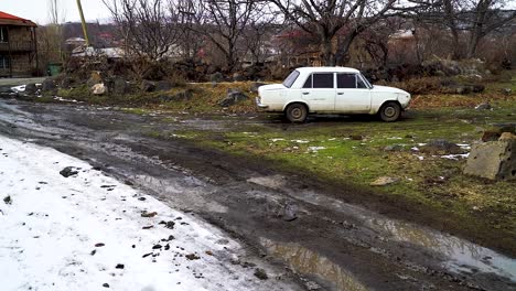 viejo coche blanco de estilo soviético apaga sospechosamente la carretera cubierta de nieve en un parche de tierra congelada cubierta por árboles