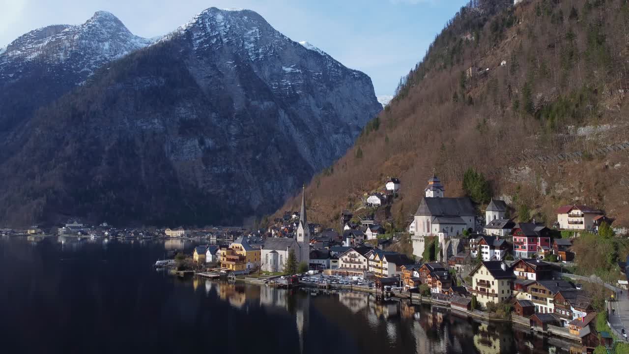 Cinematic aerial over iconic town of Hallstatt with snow-topped mountains towering above - Hallstatt, Austria