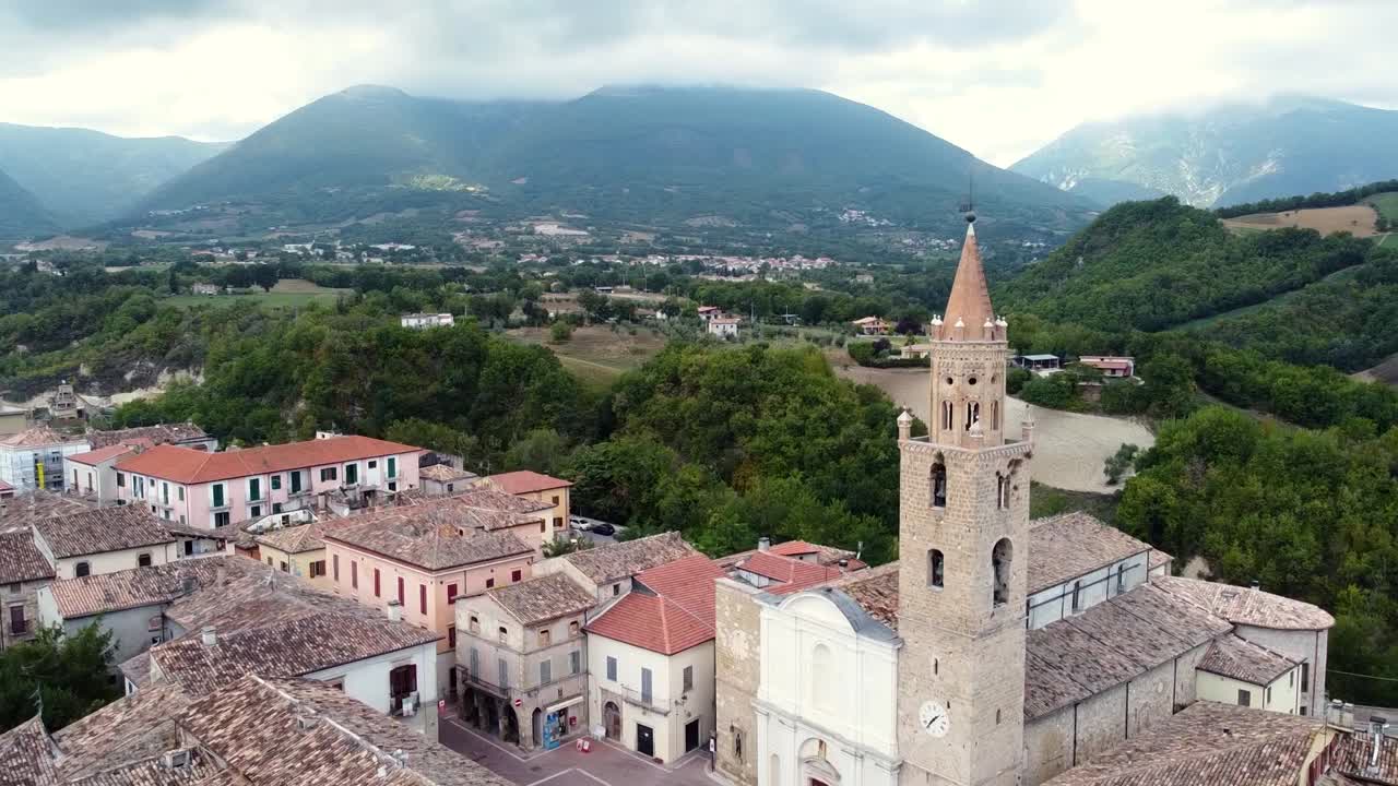 vista aérea ascendente de un campanario en un pequeño pueblo italiano en un paisaje montañoso