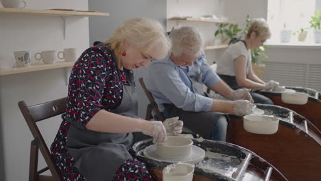 Three-elderly-people-work-on-a-potter's-wheel-in-slow-motion