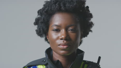 retrato de estudio de una joven policía sonriente contra un fondo plano