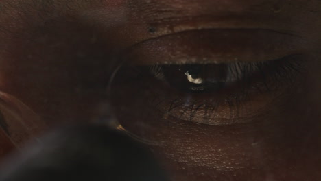 eyes of scientist in glasses analyzing specimen through microscope