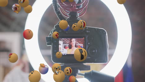 animation of emoji icons over female vlogger on camera viewer recording vlog at home