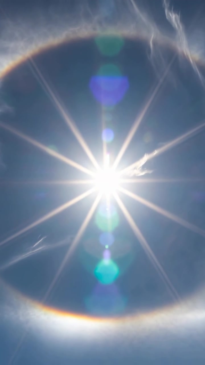 Video vertical: Destello de halo solar pulsante moviéndose de la deriva de cirros en el cielo azul por cristales de hielo.