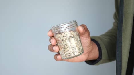 hand holding a jar of sunflower seeds