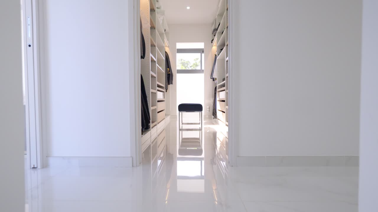 la cámara sube la escalera y revela un vestidor con armarios para la ropa