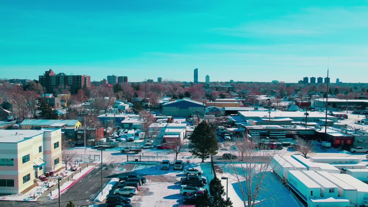 An aerial winter view following a car across Denver’s snowy streets.