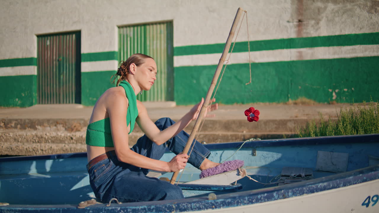 주말에 시 보트에서 막대기를 들고 있는 편안한 소녀. 빛에 아름다운 모델