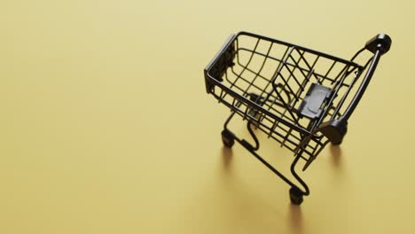 video of empty shopping trolley with copy space on yellow background