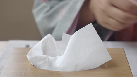 person pulling out a tissue from a box