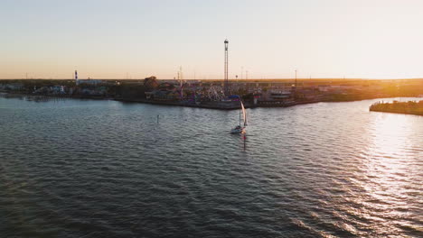 Vista-Aérea-De-Un-Barco-Navegando-Frente-Al-Paseo-Marítimo-De-Kemah,-Puesta-De-Sol-En-Texas,-Estados-Unidos