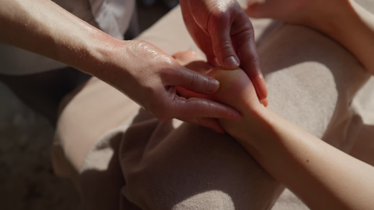 Nærbilde av hender som masserer en fot med olje for avslapning