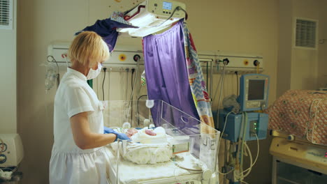 enfermera que cuida a un recién nacido en una unidad de cuidados intensivos neonatales