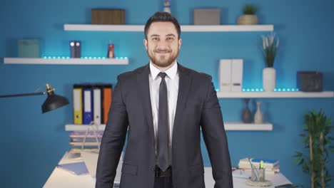 hombre de negocios lindo haciendo corazón mirando a la cámara en su oficina.