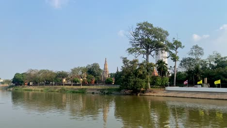 vista tranquila del río con la pagoda tradicional del templo tailandés, vegetación exuberante y cielos despejados