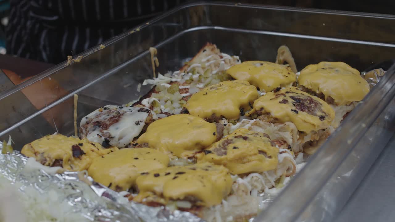 요리사는 치즈와 함께 튀긴 쇠고기 고기를 슬라이더 버거 빵과 함께 트레이에 넣습니다