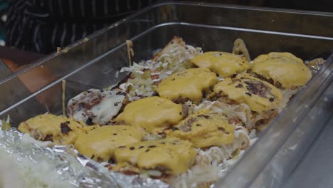 chef places fried beef meat with cheese into the tray with slider burger bun