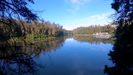 Unberührter,-Ruhiger-Wassersee-Mit-Reflexion-Des-Beruhigenden-Blauen-Himmels-Und-Umgeben-Von-Grünen-Wäldern.-Video-Aufgenommen-Am-Ooty-Lake-Tamilnadu,-Indien