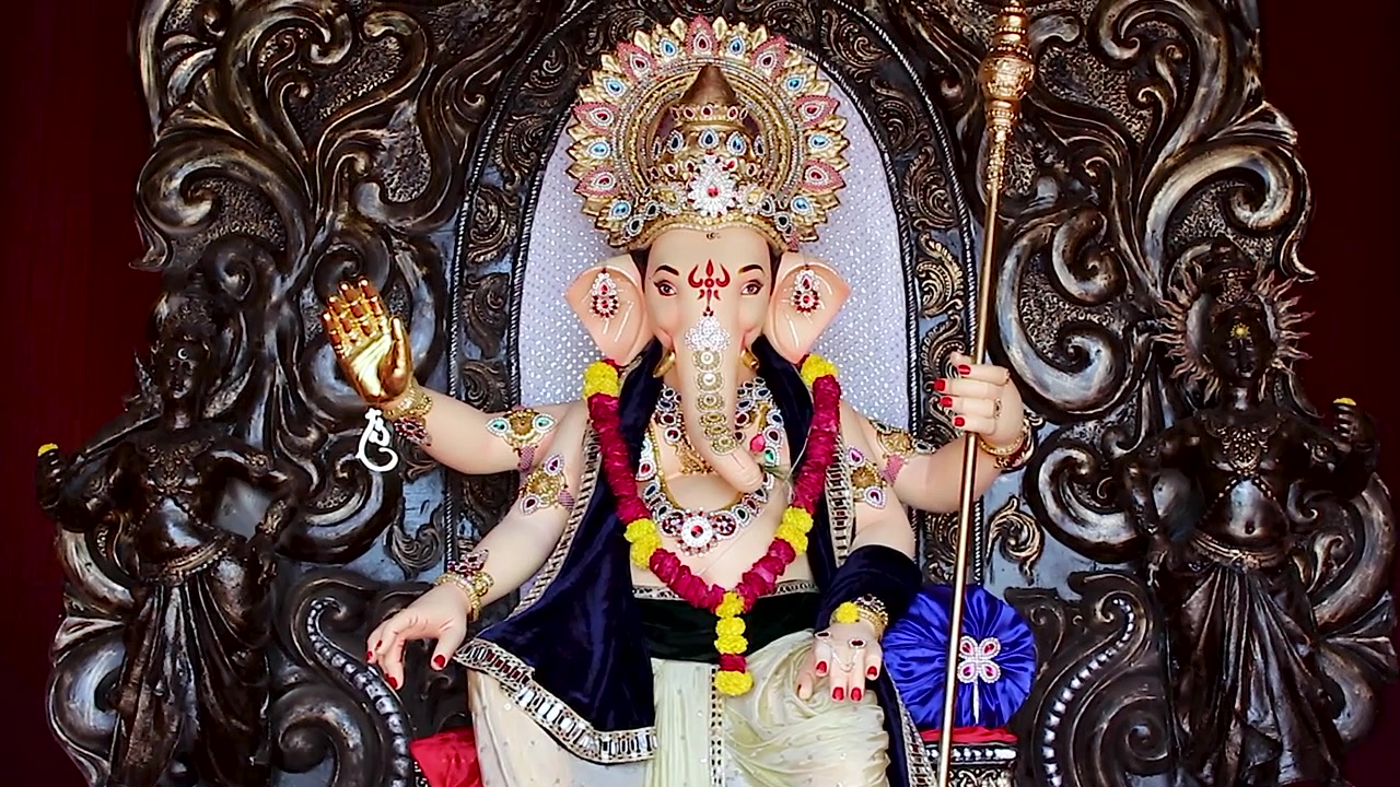 Ripresa ravvicinata con movimento tilt di un pandal durante il Ganesh Chaturthi in India, con l'idolo di Lord Ganesha adornato da ghirlande, gioielli e ornamenti d'oro durante il festival indù