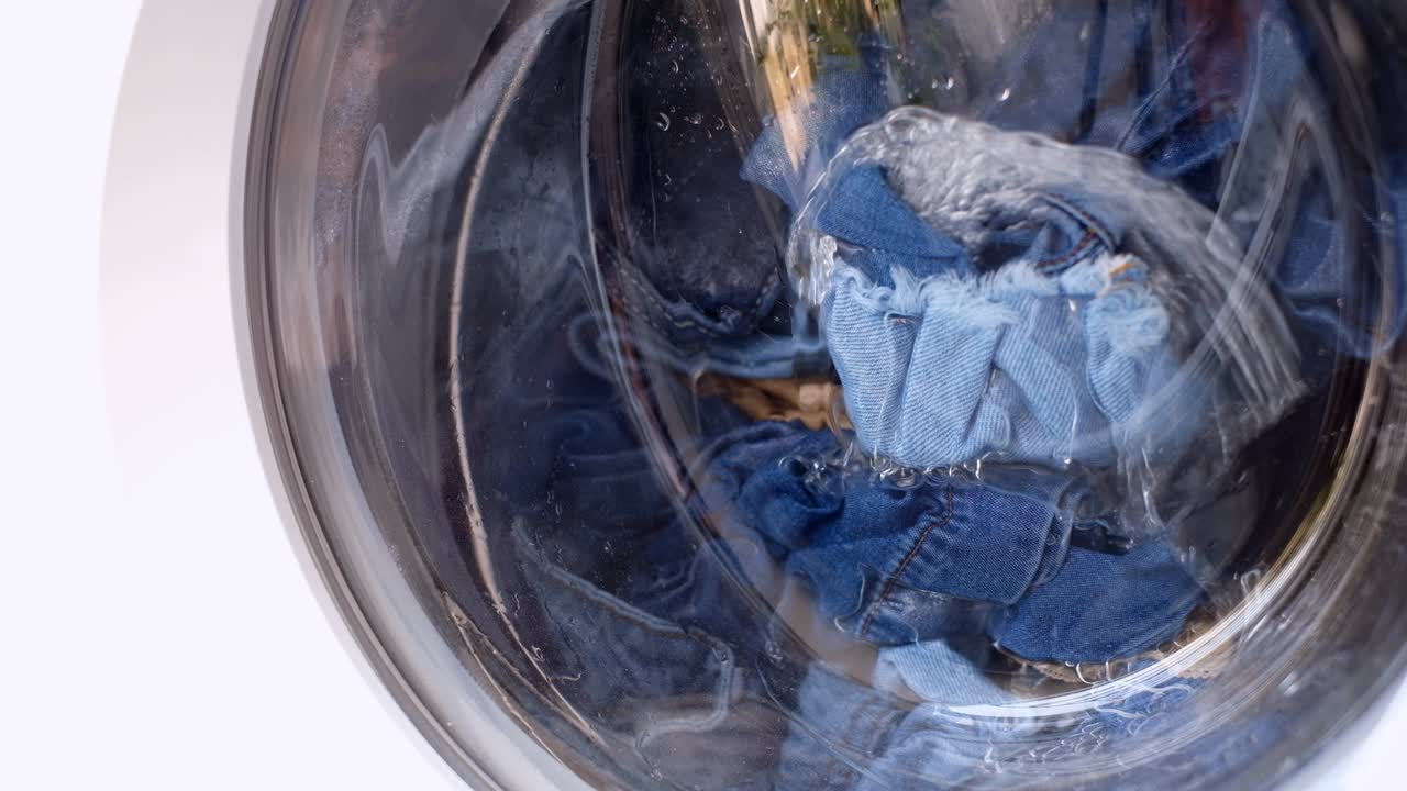 옷은 유리 문 뒤에 있는 색 자동 세탁기에서 세탁되며, 금속 드럼은 차례로 다른 방향으로 회전합니다.