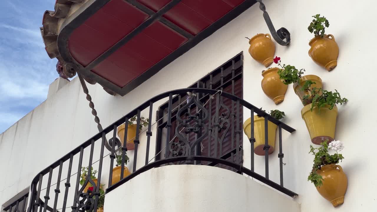 side view of a wrought-iron balcony decorated with flowerpots hanging on the wall