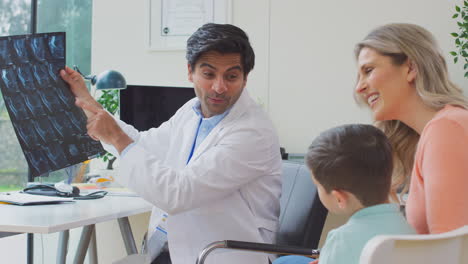 doctor in white coat with mother and son in office looking at mri or ct scans