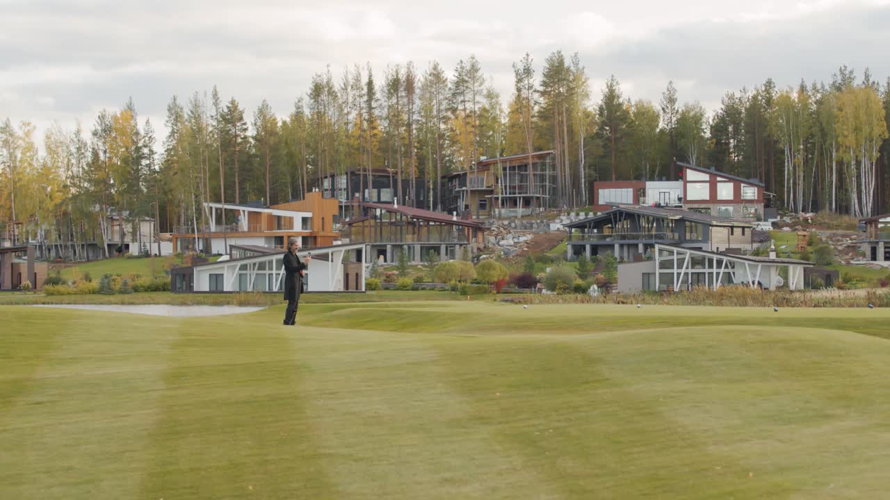 공원 도로에서 스마트폰을 사용하면서 스쿠터를 타는 젊은 우아한 사업가